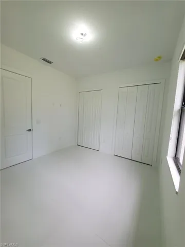 Unfurnished bedroom with tile patterned floors and multiple closets