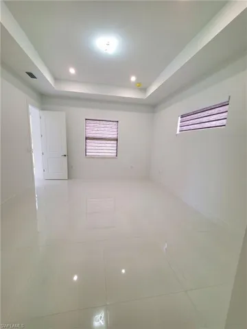 Empty room featuring light tile patterned floors and a tray ceiling