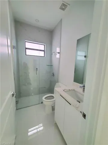 Bathroom with tile patterned flooring, vanity, toilet, and a shower with shower door