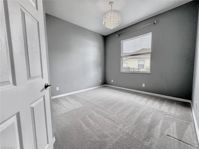 Unfurnished room featuring carpet flooring and a chandelier
