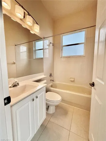 Bathroom featuring shower / tub combination, vanity, and light tile patterned flooring