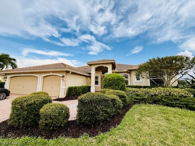 Mediterranean / spanish-style house featuring a garage, stucco siding, decorative driveway, a tiled roof, and a front lawn