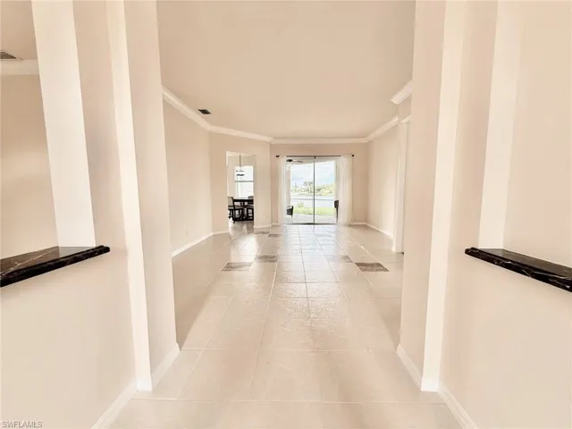 Corridor featuring ornamental molding and light tile patterned floors