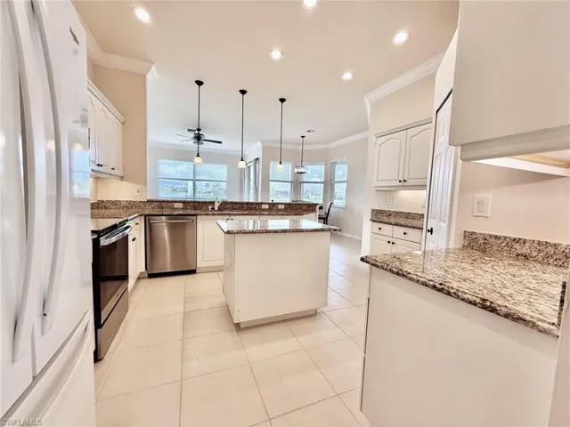 Kitchen featuring a peninsula, crown molding, stainless steel appliances, pendant lighting, and dark stone countertops
