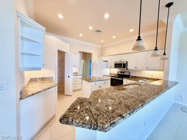 Kitchen with a kitchen island, dark stone counters, open shelves, pendant lighting, and appliances