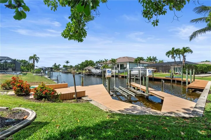 Dock with boat lift, a yard, a water view, and a residential view