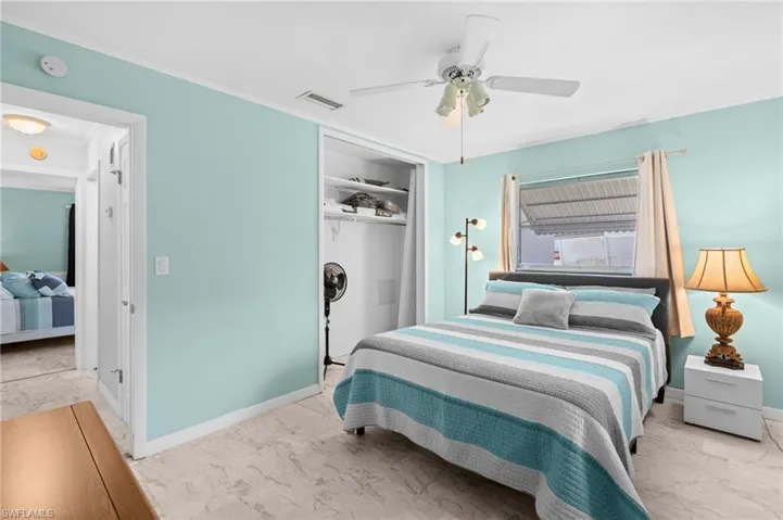 Bedroom featuring marble look tile flooring, ceiling fan, a closet, and ornamental molding