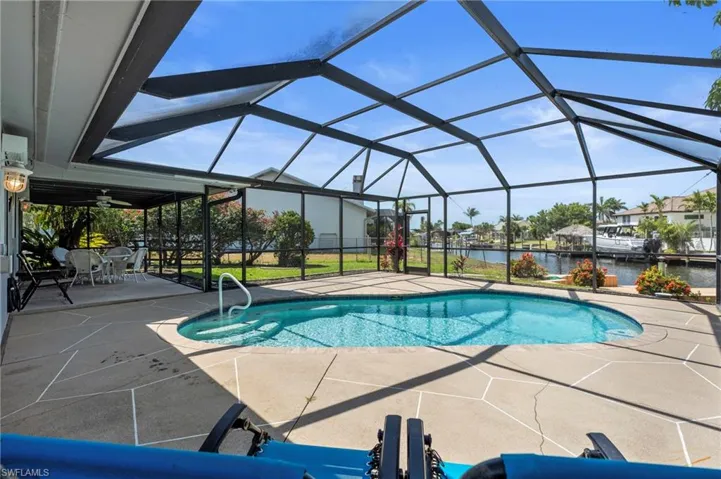 Swimming pool featuring a water view, a patio, a sunroom, and glass enclosure