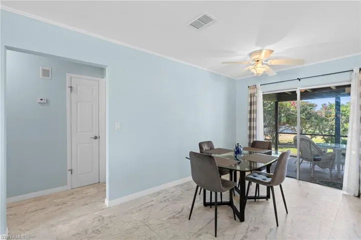 Dining area featuring light marble finish flooring, ornamental molding, and ceiling fan
