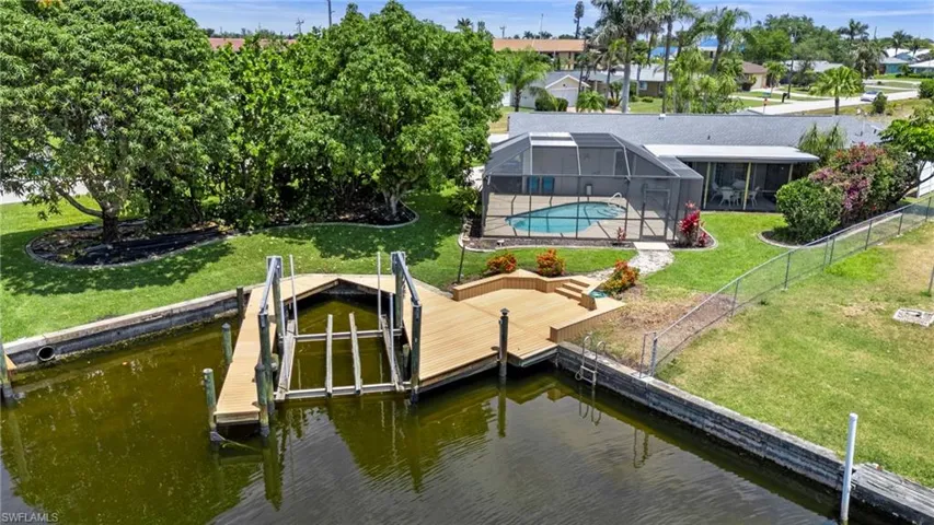 Dock with glass enclosure, a yard, an outdoor pool, a water view, and boat lift