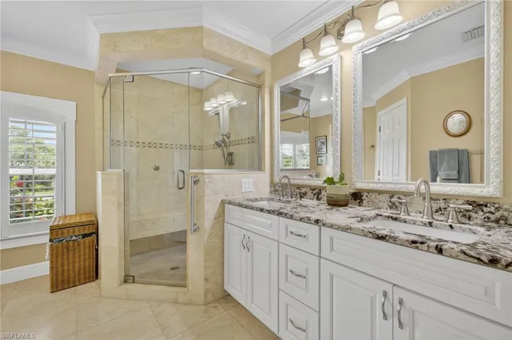 Bathroom featuring a stall shower, ornamental molding, and double vanity