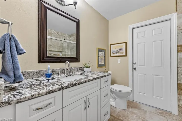 Full bathroom featuring vanity, a stall shower, and stone tile floors