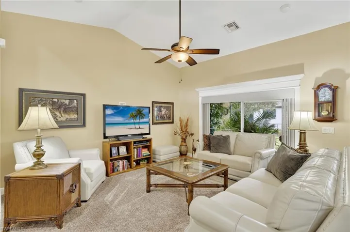 Carpeted living room with vaulted ceiling and a ceiling fan