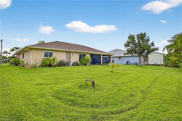 Back of house featuring stucco siding and a yard