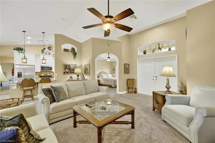 Carpeted living area featuring a ceiling fan and high vaulted ceiling