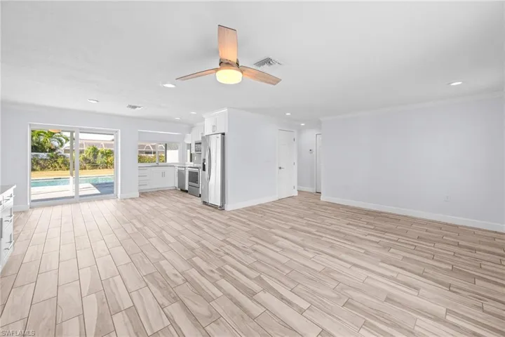 Unfurnished living room featuring light wood-style flooring, a ceiling fan, crown molding, and recessed lighting