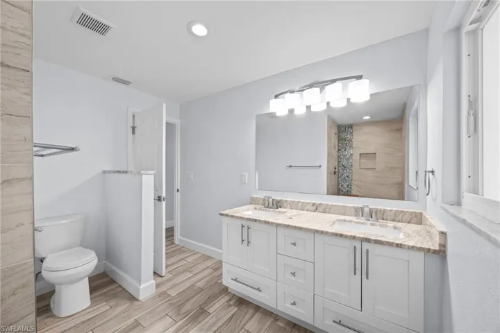 Bathroom featuring double vanity, wood finish floors, a shower with curtain, and recessed lighting
