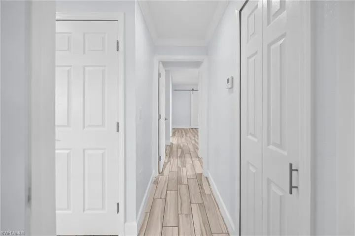 Corridor with wood finish floors and ornamental molding