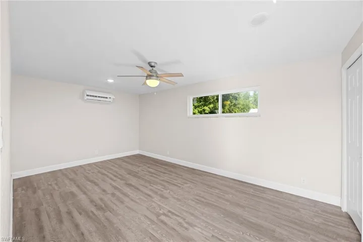 Unfurnished bedroom with light wood finished floors, ceiling fan, a closet, recessed lighting, and an AC wall unit