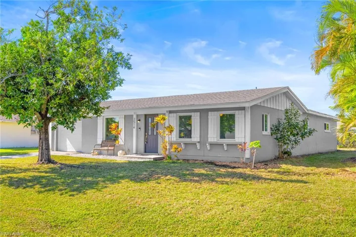 Single story home with a front yard, a shingled roof, and a porch