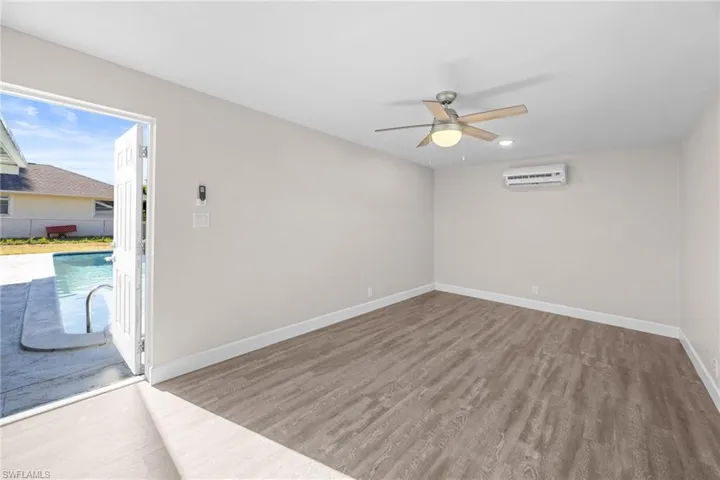 Unfurnished room featuring light wood-type flooring, ceiling fan, and an AC wall unit