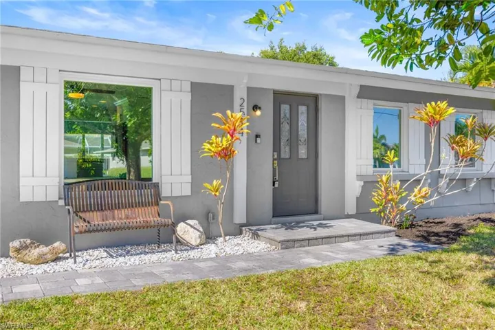 View of exterior entry with a yard and stucco siding