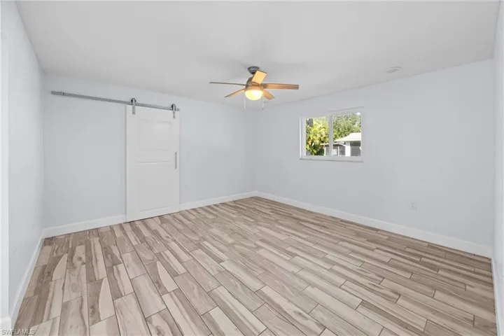 Unfurnished room featuring wood tiled floors, a barn door, and ceiling fan