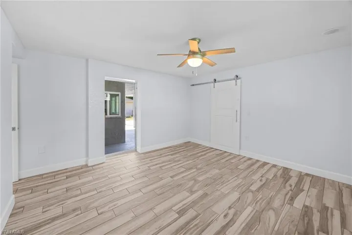 Spare room featuring wood finish floors, a barn door, and ceiling fan