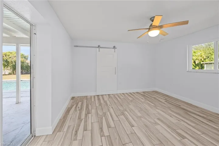 Spare room featuring a barn door, wood tiled floors, and ceiling fan