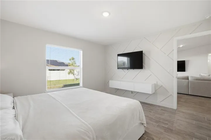 Bedroom with wood tiled floors, an accent wall, and recessed lighting