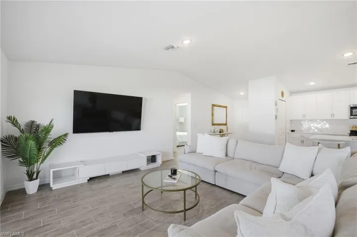 Living area with wood finish floors, lofted ceiling, and recessed lighting