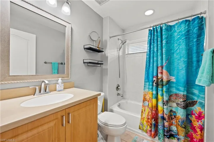 Full bathroom featuring shower / bath combo, vanity, tile patterned floors, and toilet