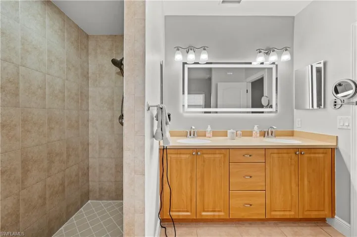 Bathroom featuring tiled shower, tile patterned flooring, and vanity