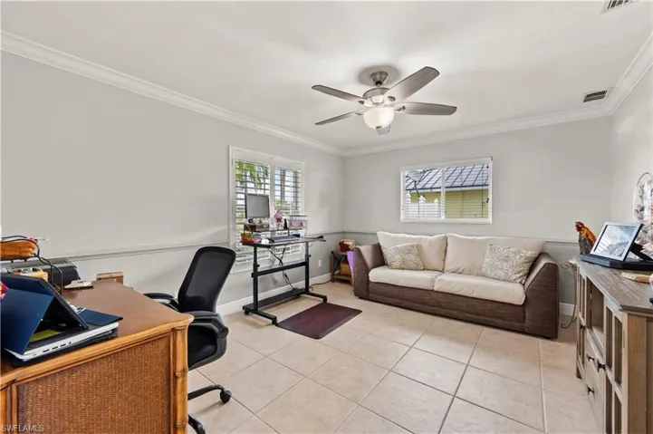 Home office featuring ceiling fan, light tile patterned flooring, and ornamental molding