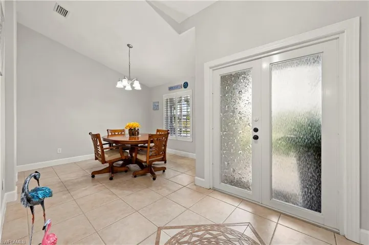 Dining room featuring lofted ceiling, an inviting chandelier, and light tile patterned floors