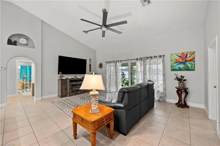 Living room featuring high vaulted ceiling, light tile patterned flooring, and ceiling fan
