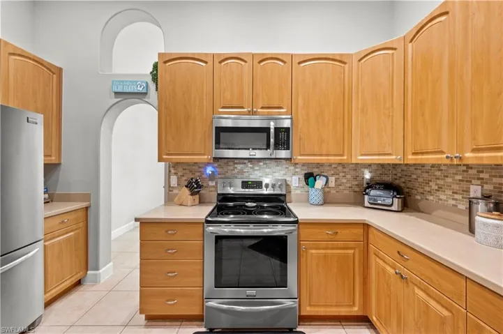 Kitchen featuring light tile patterned floors, tasteful backsplash, and appliances with stainless steel finishes