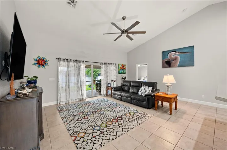 Tiled living room featuring lofted ceiling and ceiling fan