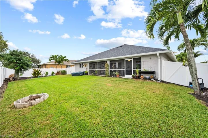Rear view of property with a fire pit, a sunroom, and a lawn