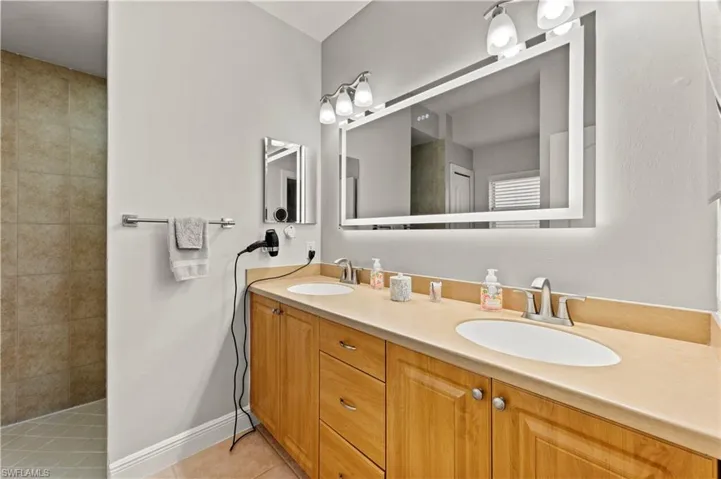 Bathroom featuring tile patterned flooring, a tile shower, and vanity