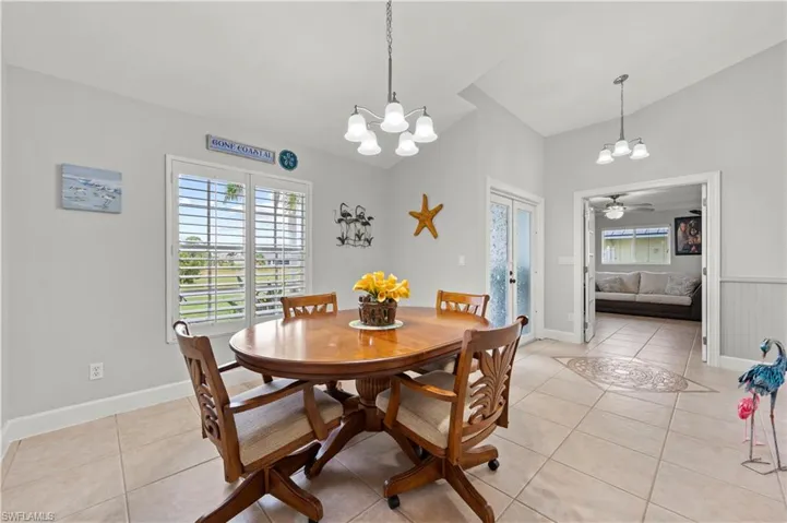 Tiled dining room featuring ceiling fan with notable chandelier