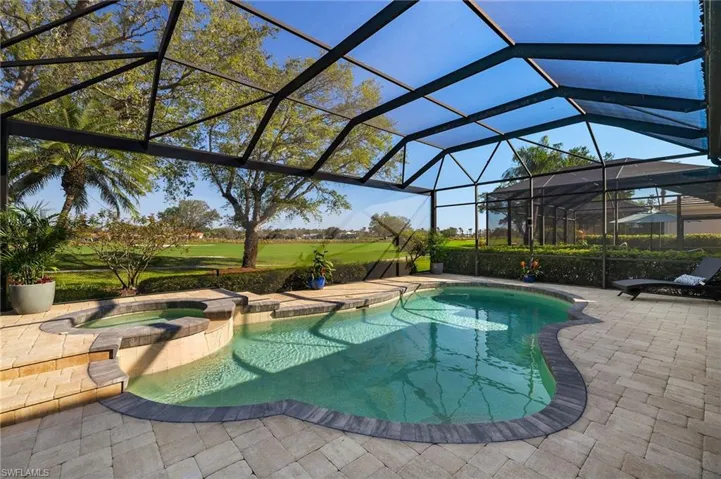 View of swimming pool featuring a lanai, a pool with connected hot tub, and a patio