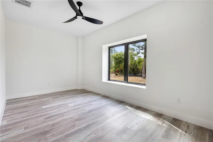 Empty room with baseboards, ceiling fan, visible vents, and wood finished floors