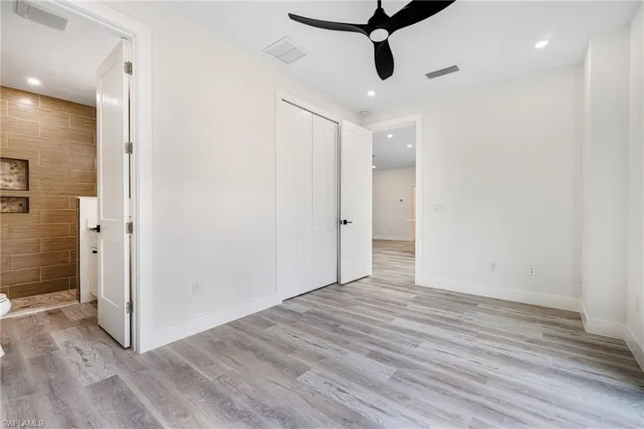 Unfurnished bedroom featuring ensuite bathroom, visible vents, and light wood-type flooring