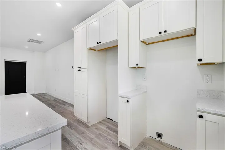 Kitchen featuring recessed lighting, light stone counters, light wood-style floors, visible vents, and white cabinets