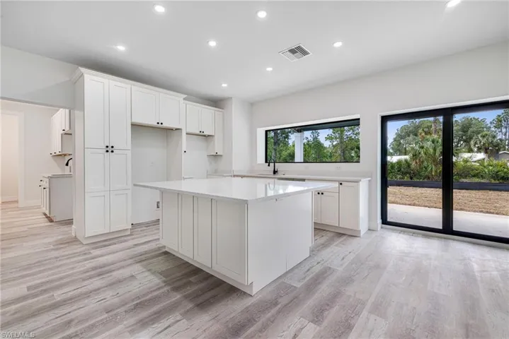Kitchen with white cabinetry, a kitchen island, and light wood-style floors