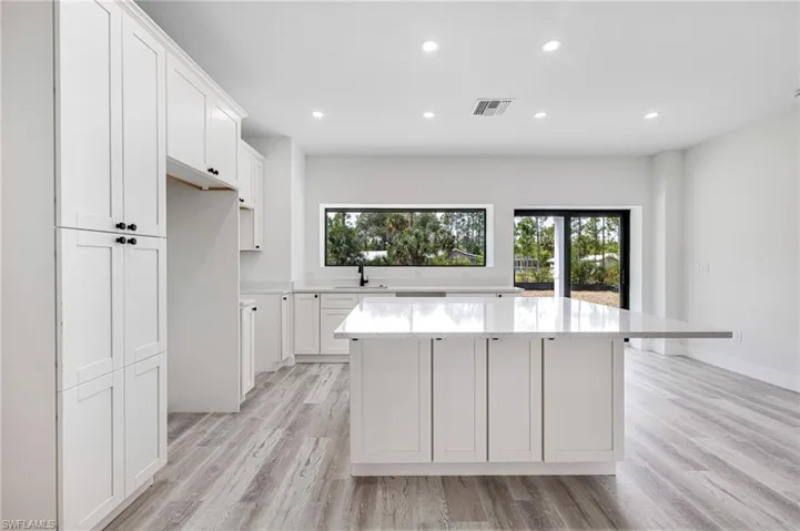 Kitchen with a sink, a kitchen island, light wood-type flooring, visible vents, and recessed lighting