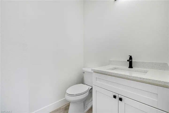 Bathroom with baseboards, toilet, vanity, and wood finished floors
