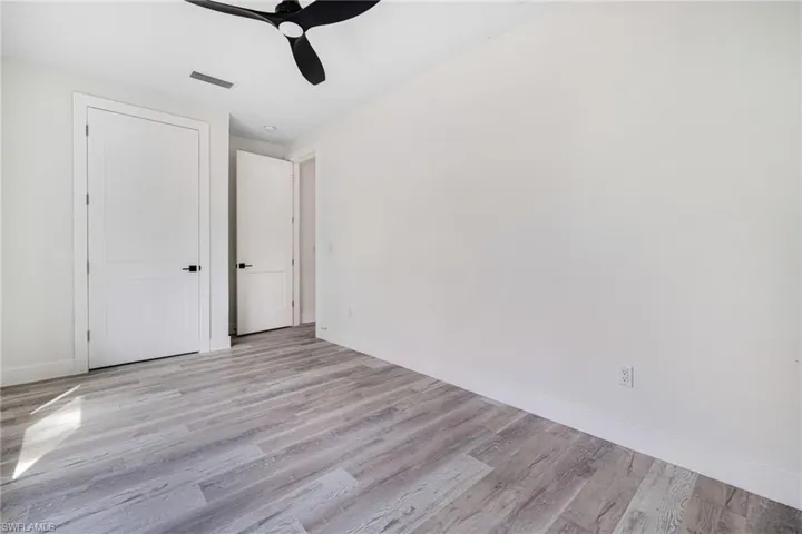 Unfurnished bedroom featuring a closet, visible vents, baseboards, a ceiling fan, and light wood-type flooring