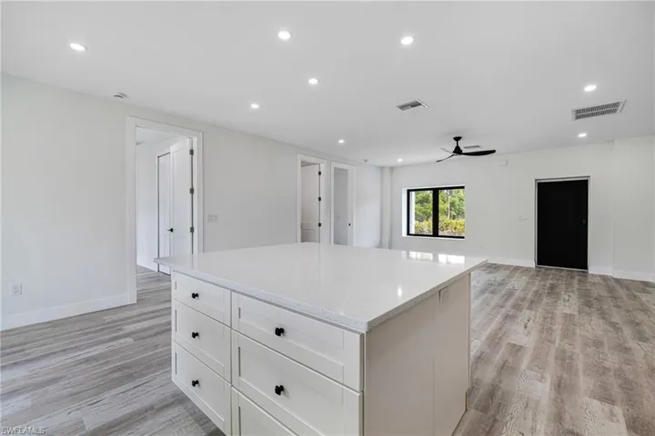 Kitchen with light wood-style flooring, a kitchen island, recessed lighting, and visible vents